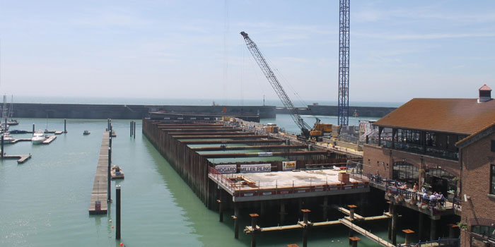 Op de foto's van dit werk in Brighton, Groot-Brittannië is de voortgang van het werk en de functie van de door Sterk geplaatste bouwkuip goed te zien.