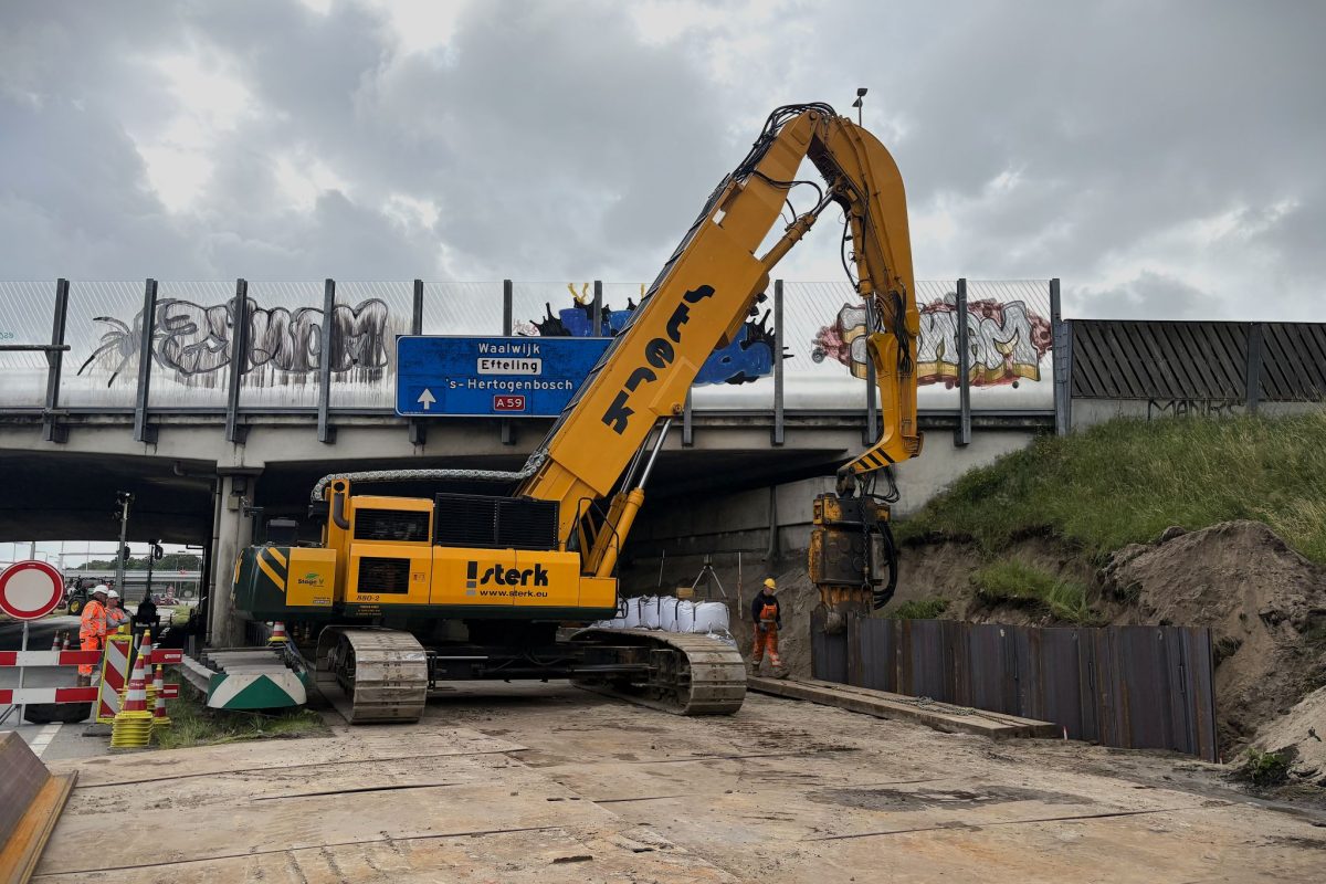Trillend aanbrengen startplanken damwand bij viaduct Hooipolder Funderingsmachine van Sterk trilt de startplanken van de damwand bij viaduct knooppunt Hooipolder